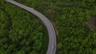 Sırbistan 'da yeşil ve manzara taşımacılığı ve seyahat konseptiyle çevrili dolambaçlı yol boyunca giden bahar aracı otomobili sırasında, bir dağ sırasındaki eğimli asfalt bir yolun hava aracı görüntüleri