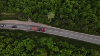 Sırbistan 'da yeşil ve manzara taşımacılığı ve seyahat konseptiyle çevrili dolambaçlı yol boyunca giden bahar aracı kamyonları sırasında bir dağ sırasındaki eğri asfalt bir yolun hava aracı görüntüleri