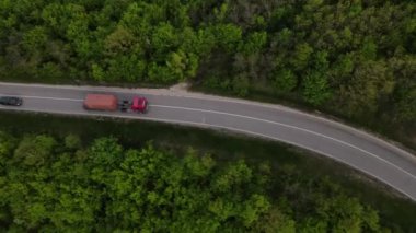 Sırbistan 'da yeşil ve manzara taşımacılığı ve seyahat konseptiyle çevrili dolambaçlı yol boyunca giden bahar aracı kamyonları sırasında bir dağ sırasındaki eğri asfalt bir yolun hava aracı görüntüleri