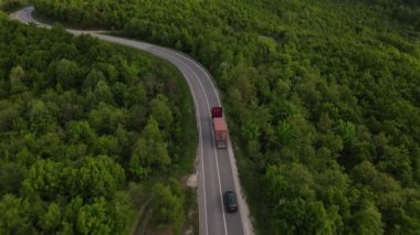 Sırbistan 'da yeşil ve manzara taşımacılığı ve seyahat konseptiyle çevrili dolambaçlı yol boyunca giden bahar aracı kamyonları sırasında bir dağ sırasındaki eğri asfalt bir yolun hava aracı görüntüleri