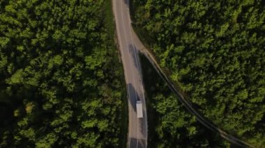 Sırbistan 'da yeşil ve manzara taşımacılığı ve seyahat konseptiyle çevrili dolambaçlı yol boyunca giden bahar aracı kamyonları sırasında bir dağ sırasındaki eğri asfalt bir yolun hava aracı görüntüleri