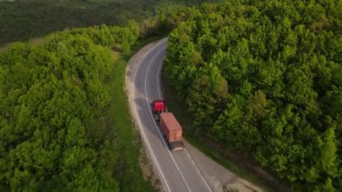 Sırbistan 'da yeşil ve manzara taşımacılığı ve seyahat konseptiyle çevrili dolambaçlı yol boyunca giden bahar aracı kamyonları sırasında bir dağ sırasındaki eğri asfalt bir yolun hava aracı görüntüleri