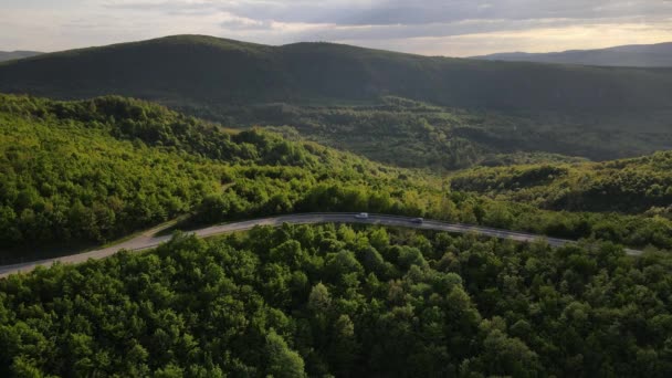 在塞尔维亚 春车沿着蜿蜒的公路行驶时 在山脉上一条弯曲的沥青路面的空中无人驾驶镜头 周围环绕着绿地和景观 交通和旅行的概念 — 图库视频影像