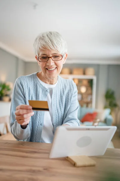 stock image One mature senior woman grandmother sit at home use credit or debit card for online shopping browse internet stores buying stuff real people copy space