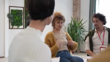 Bir grup insan, iki terapist ve merkezde bir kadınla bir çemberin içinde oturuyor ve ona duygusal destek sağlıyorlar.