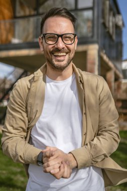 Bir modern yetişkin beyaz erkek portresi sakallı ve gözlüklü erkek evinin önünde duruyor. Mutlu, kendinden emin fotokopi odası.