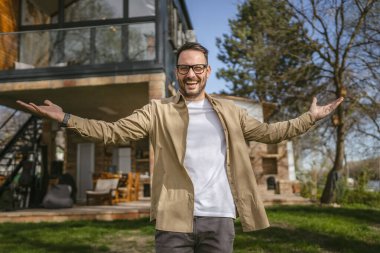 Bir modern yetişkin beyaz erkek portresi sakallı ve gözlüklü erkek evinin önünde duruyor. Mutlu, kendinden emin fotokopi odası.