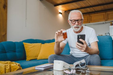 Son sınıflardan biri elinde ilaç ya da takviye ilaç şişesiyle kanepede oturuyor. Akıllı telefon, ilaç tableti, ağrı kesici ya da ilaç almaya hazır vitamin talimatları okuyor.