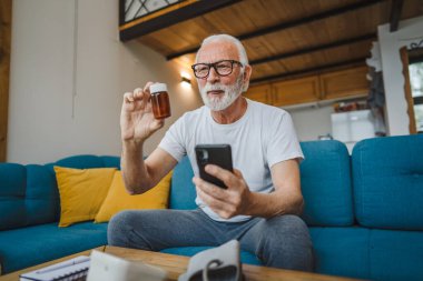 Son sınıflardan biri elinde ilaç ya da takviye ilaç şişesiyle kanepede oturuyor. Akıllı telefon, ilaç tableti, ağrı kesici ya da ilaç almaya hazır vitamin talimatları okuyor.