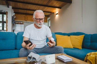 Son sınıflardan biri elinde ilaç ya da takviye ilaç şişesiyle kanepede oturuyor. Akıllı telefon, ilaç tableti, ağrı kesici ya da ilaç almaya hazır vitamin talimatları okuyor.
