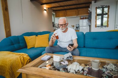 Son sınıflardan biri elinde ilaç ya da takviye ilaç şişesiyle kanepede oturuyor. Akıllı telefon, ilaç tableti, ağrı kesici ya da ilaç almaya hazır vitamin talimatları okuyor.