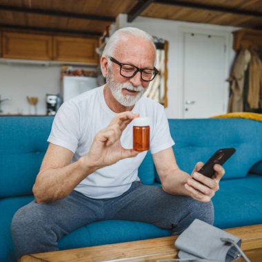 Son sınıflardan biri elinde ilaç ya da takviye ilaç şişesiyle kanepede oturuyor. Akıllı telefon, ilaç tableti, ağrı kesici ya da ilaç almaya hazır vitamin talimatları okuyor.