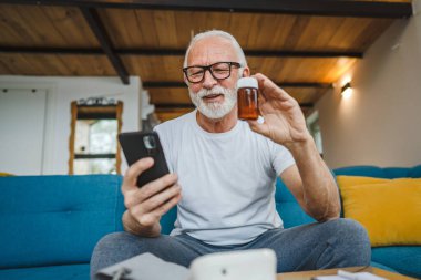 Son sınıflardan biri elinde ilaç ya da takviye ilaç şişesiyle kanepede oturuyor. Akıllı telefon, ilaç tableti, ağrı kesici ya da ilaç almaya hazır vitamin talimatları okuyor.