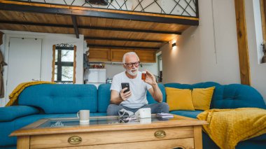 Son sınıflardan biri elinde ilaç ya da takviye ilaç şişesiyle kanepede oturuyor. Akıllı telefon, ilaç tableti, ağrı kesici ya da ilaç almaya hazır vitamin talimatları okuyor.
