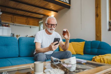 Son sınıflardan biri elinde ilaç ya da takviye ilaç şişesiyle kanepede oturuyor. Akıllı telefon, ilaç tableti, ağrı kesici ya da ilaç almaya hazır vitamin talimatları okuyor.