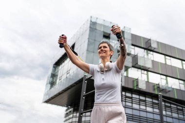 Bir kadın olgun ya da yaşlı, kauçuk elastik direnç bantlı beyaz kadın eğitimi. Açık spor salonunun spor salonundaki tüplerde. Sağlıklı yaşam tarzı konsepti.