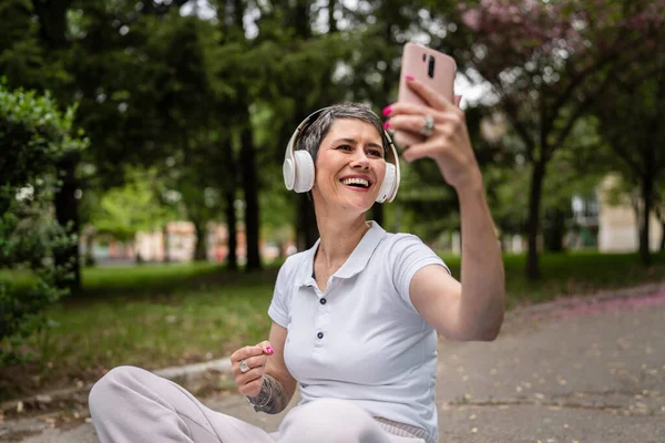 Yetişkin Bir Son Sınıf Beyaz Kadın Kulaklıkları Ayarlıyor Açık Havada — Stok fotoğraf
