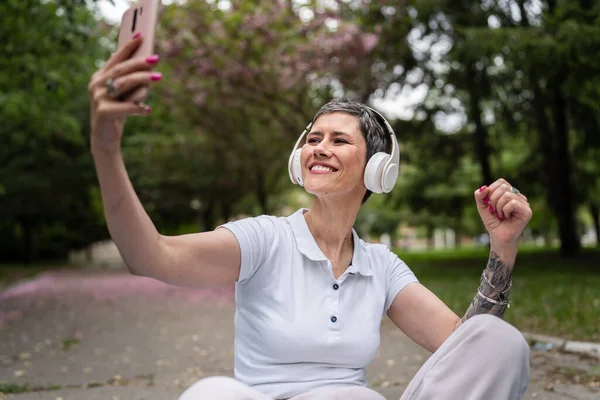 Yetişkin Bir Son Sınıf Beyaz Kadın Kulaklıkları Ayarlıyor Açık Havada — Stok fotoğraf