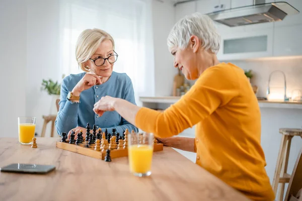 两个年长的成熟女性高加索女性女性朋友或姐妹在家里玩棋盘休闲游戏玩得开心 一起呆在家里明亮的影印空间里 — 图库照片