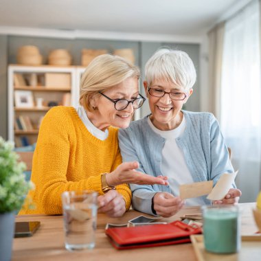 Yetişkin kadın arkadaşlar ya da kız kardeşler aile fotoğraflarına bakıyor. İki beyaz kadın evde oturup gülümserken gerçek insanlar uzayı kopyalıyor.