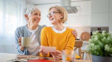 Yetişkin kadın arkadaşlar ya da kız kardeşler aile fotoğraflarına bakıyor. İki beyaz kadın evde oturup gülümserken gerçek insanlar uzayı kopyalıyor.