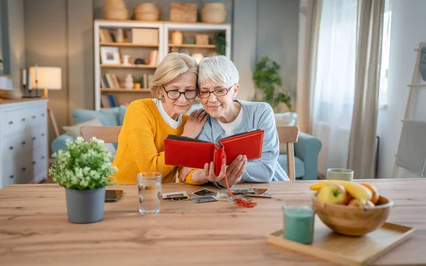 年长的成熟女性朋友或姐妹看家庭相册两张高加索女性坐在家里开心地笑着 同时取消了记忆真实的人复制的空间 — 图库照片