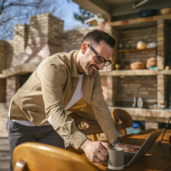 stock image One man caucasian modern male stand on the balcony terrace alone at home wear shirt work on laptop computer in day remote happy smile confident success concept copy space