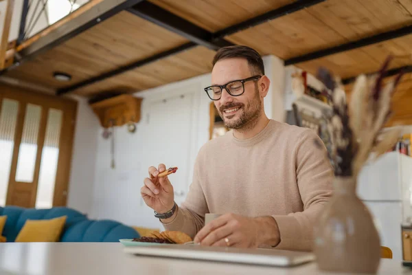 一位成年男子坐在家中餐桌旁 在准备吃早餐的饼干上放果酱 享受在家庭环境中放松的小吃 — 图库照片