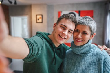 Delikanlı, genç bir adam ve olgun bir kadın anne ve oğlu evde kendi portrelerini çekiyorlar.