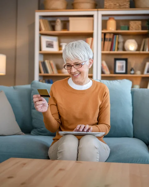 stock image One mature senior woman grandmother sit at home use credit or debit card for online shopping browse internet stores buying stuff on discount sale real people copy space use digital tablet