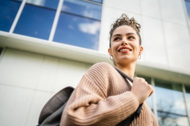 Genç yetişkin bir kadın beyaz kadın dışarıda durup mutlu bir portre çiziyor.