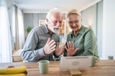 Yaşlı bir çift, Kafkasyalı yaşlı bir adam ve bir kadın, emekli bir koca ve bir büyükanne, dijital tablet kullanarak evlerinde video çekiyor. Parlak bir odada, gerçek insanlar, aile kavramını taklit ediyorlar.