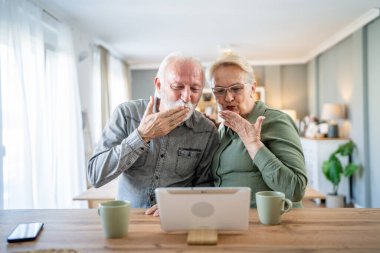 Yaşlı bir çift, Kafkasyalı yaşlı bir adam ve bir kadın, emekli bir koca ve bir büyükanne, dijital tablet kullanarak evlerinde video çekiyor. Parlak bir odada, gerçek insanlar, aile kavramını taklit ediyorlar.