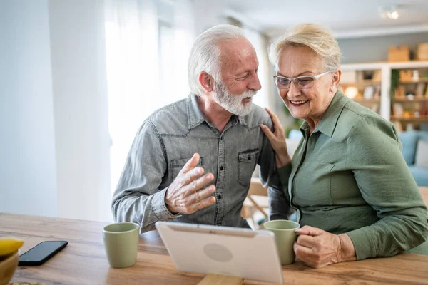 Senior couple caucasian old man and woman husband and wife pensioner grandfather and grandmother use digital tablet for online video call at home in bright room real people family concept copy space