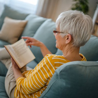Yetişkin, yaşlı, Kafkasyalı, emekli, modern, kitap okuyan bir kadın gözlük takıyor.