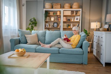 Yetişkin, yaşlı, Kafkasyalı, emekli, modern, kitap okuyan bir kadın gözlük takıyor.