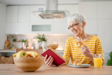 Yetişkin, yaşlı, Kafkasyalı, emekli, modern, kitap okuyan bir kadın gözlük takıyor.