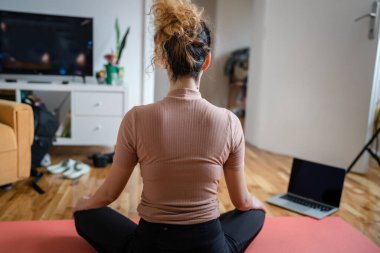 Evde meditasyon yapan bir kadın yoga yapıyor. Kendine dikkat et.