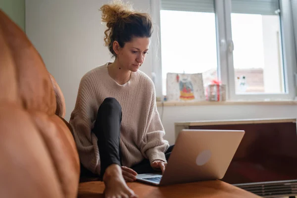 1人の女性成熟した白人女性に座っているソファベッドの上で自宅作業ノートパソコンやオンラインショッピングのためのインターネットを参照リアル人々コピースペース — ストック写真