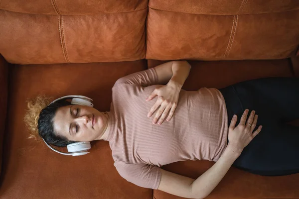 オンラインガイド付き瞑想のためのヘッドフォンを使用して1人の女性大人の白人女性千年紀自宅でソファベッドで目を閉じてマインドフルネスヨガを練習自己ケアコンセプトコピースペース — ストック写真