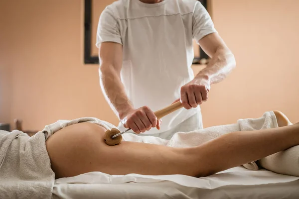 stock image Unknown Caucasian woman having madero therapy massage anti-cellulite treatment by professional therapist holding wooden tools in hands in studio or salon with copy space