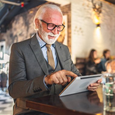 Bir üst düzey Kafkas erkek iş adamı Kafe 'de dijital tablet kullanıyor. Kıyafet fotokopi alanı kullanıyor.
