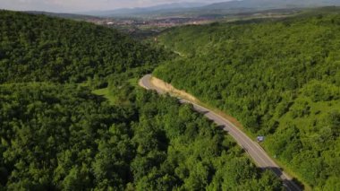 Hava aracının otomobil üzerindeki görüntüsü ilkbahar güneşli bir günde dağlık alanda ağaçların arasından geçerek - Sırbistan 'da Tresibaba Knjazevac - seyahat yolculuğu ve tatil konsepti araba sürüşü