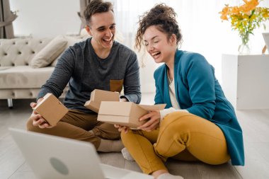 Genç çift erkek ve kadın erkek ve kız arkadaş ya da karı koca hediyelerini evde değiştirip birbirlerine hediye veriyorlar ve mutlu bir gülümseme açıyorlar sevgililer günü bayramı ya da doğum günü kutluyorlar.