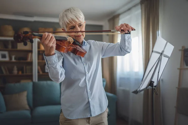成熟したシニア白人女性は自宅でバイオリンの練習を再生することを学ぶ — ストック写真