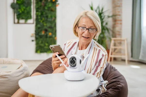 Yetişkin Bir Beyaz Kadın Modern Güvenlik Kamerası Cep Telefonunu Elinde — Stok fotoğraf
