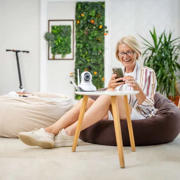 Een Volwassen Blanke Vrouw Houdt Thuis Moderne Bewakingscamera Mobiele Telefoon — Stockfoto