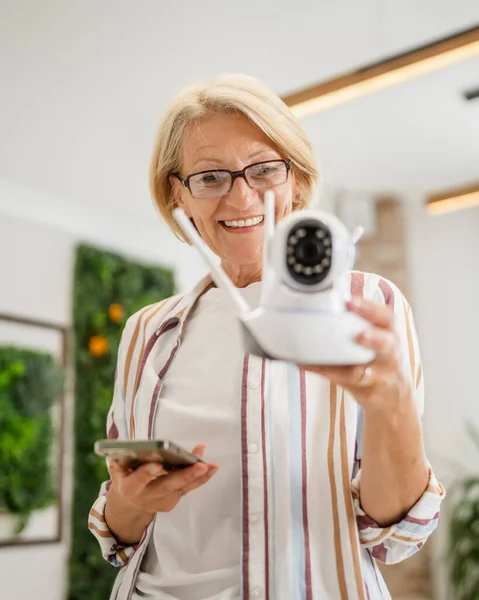 Een Volwassen Blanke Vrouw Houdt Thuis Moderne Bewakingscamera Mobiele Telefoon — Stockfoto