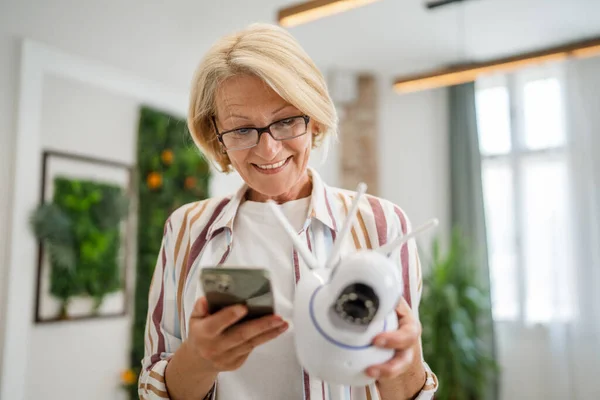 Одна Взрослая Белая Женщина Держит Дома Современную Камеру Наблюдения Мобильный — стоковое фото