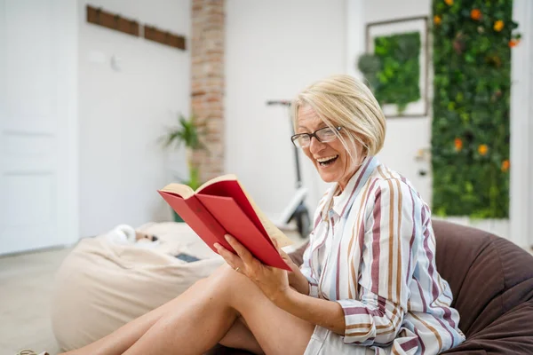 一位成熟的高加索女人在明亮的房间里穿着眼镜在家里看书真人复制空间 — 图库照片